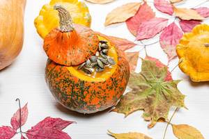 Autumn background with colorful dry leaves and pumpkins on a white wooden background