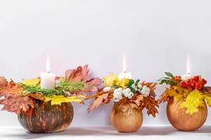 Autumn background with glowing candles, pumpkin and yellow leaves