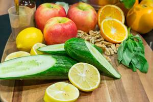 Autumnal season ingredients: Cut cucumbers, apples, walnuts and citrus fruits on a wooden board