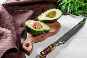Avocado and knife on wooden table background. Healthy food concept