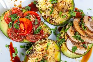 Avocado halves stuffed with mushrooms, cheese, tomatoes and herbs. Top view