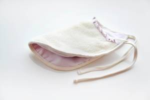 Baby-Lätzchen aus flauschigem Stoff  in weiß und rosa  vor weißem Hintergrund
