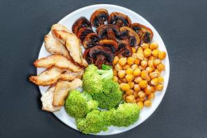 Baked chicken breast and mushrooms with chickpeas and fresh broccoli. Top view