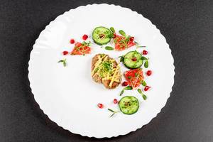 Baked chicken with grated cheese and a garnish of cucumber, micro greens and fruits, top view (Flip 2020)