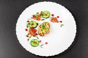 Baked chicken with grated cheese and a garnish of cucumber, micro greens and fruits, top view