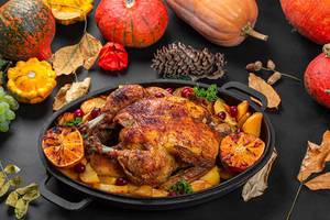 Baked chicken with potatoes, orange and dogwood berries. Background for autumn holidays