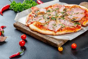 Baked homemade pizza with ham, mushrooms and cheese on a black background
