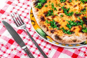 Baked khachapuri with parsley and cheese on the table with knife and fork