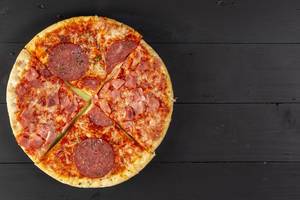 Baked Pizza with Sausage on the black wooden table (Flip 2019)