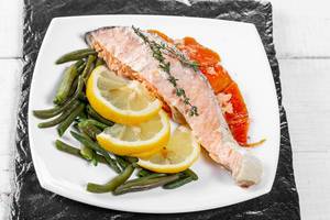 Baked salmon garnished with asparagus and carrot with herbs