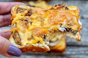Baked sandwich with mushrooms and cheese in the hand of a woman