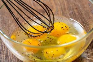 Beaten eggs in a bowl with whisk