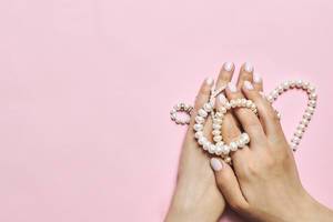 Beautiful female hands with manicure holding pearls.jpg