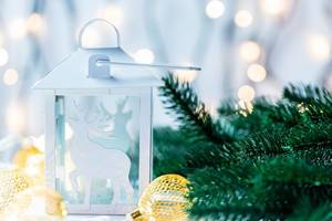 Beautiful white Christmas lantern on bokeh background of garlands