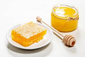 Bee products with honey and sweet honeycomb on white background, healthy products, organic natural ingredients concept