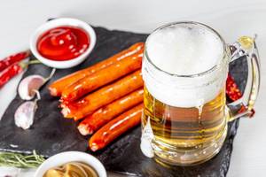 Beer mug with sauces and sausages on a black stone tray (Flip 2019)