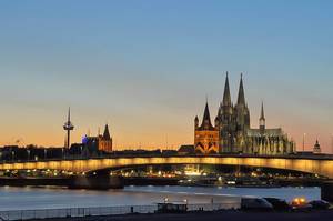 Beleuchtete Brücke und Wahrzeichen einer deutschen Großstadt bei Abenddämmerung
