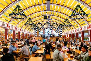 Besucher in Lederhose trinken Bier im Löwenbräu-Festzelt beim Oktoberfest in München