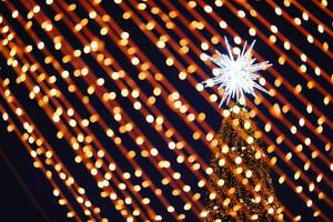 Big star on top of Christmas tree, closeup view through the lights (Flip 2019)