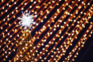 Big star on top of Christmas tree, closeup view through the lights