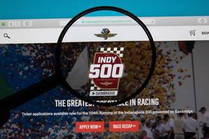 Bildschirm zeigt Internetseite des Motorsport-Events in Indianapolis mit Lupe über Logo des Indy 500
