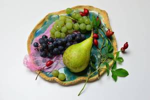 Birne mit gemischten Weintrauben auf blauem Tonteller