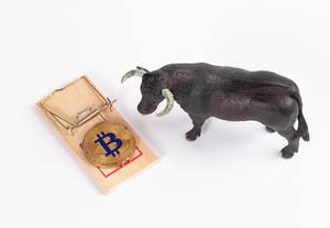 Bitcoin in a mousetrap surrounded by a bull symbolising decreasing bitcoin stocks