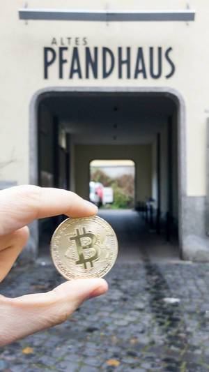 Bitcoin Münze und Altes Pfandhaus im Hintergrund