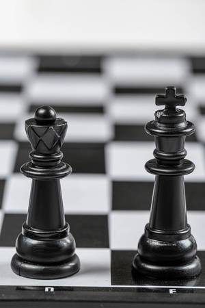 Black king and Queen chess pieces stand on a chessboard