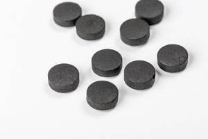 Black tablets of activated carbon on a white background (Flip 2020)