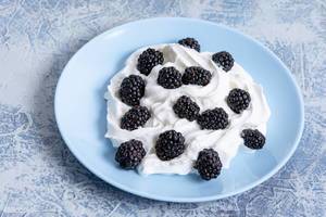 Blackberries with white cream on the plate