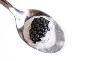 Blackberries with white cream on the spoon
