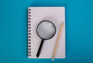 Blank notebook with pencil and magnifying glass