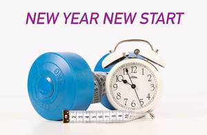 Blaue Hantel mit einem Maßband umwickelt, neben einem weißen Wecker und dem Text "New Year, New Start" (Neuanfang im neuen Jahr)