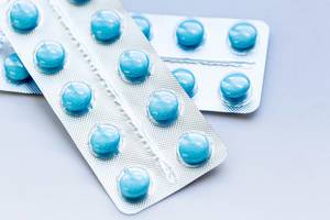 Blaue Tabletten in Verpackungen, auf weißer Oberfläche