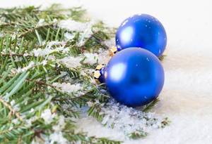 Blaue Weihnachtsbaumkugeln und ein Ast bedeckt mit Kunstschnee
