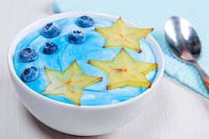 Blaues Frühstück mit gesunden Haferflocken, Karambole und Heidelbeeren auf gefärbtem Joghurt