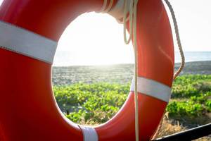 Blick auf den Strand durch einen orangefarbenen Rettungsring