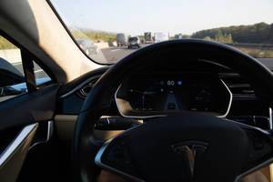 Blick über das Lenkrad des Elektroauto Tesla Model S im Autopilot auf der Autobahn