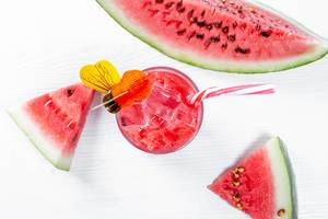 Blick von oben auf erfrischenden Sommerdrink aus Wassermelonensaft neben Melonenstücken