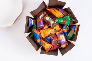Blick von oben auf geöffnete Kartonbox gefüllt mit Schokolade-Mix von J.D. Gross auf weißem Tisch
