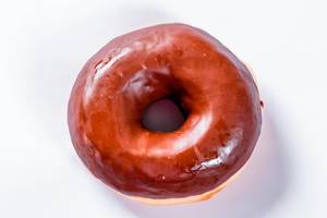Blick von oben auf mit Schokolade überzogenen Donut vor weißem Hintergrund