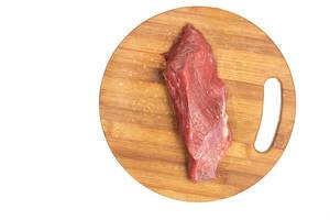 Blick von oben auf saftiges Stück rohes Rindfleisch auf hölzernem Küchenbrett vor weißem Hintergrund