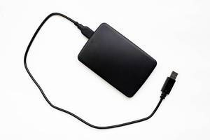 Blick von oben auf schwarze externe Festplatte mit USB-Kabel vor weißem Hintergrund