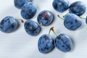 Blue ripe plums on white table (Flip 2019)