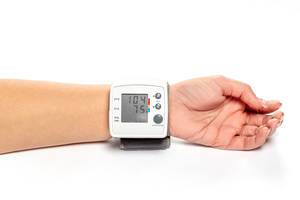 Blutdruckmessgerät und tonometer am Handgelenk einer Frau auf weißem Hintergrund