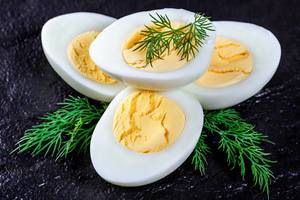 Boiled chicken eggs with dill sprigs on black stone