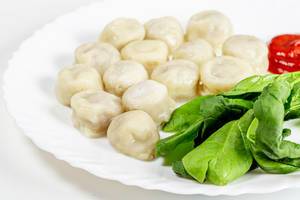 Boiled dumplings with spinach and tomato sauce