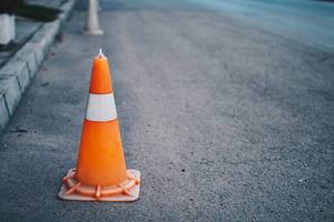 Bokeh Photo of Orange Traffic Pylon standing on side of the road