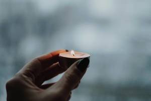 Bokeh Photo of Person holding burning candle with romantic dark background